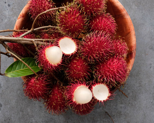 Fresh rambutan fruit from Hawaii. Image of fresh rambutan in a bowl with a few fruits peeled open to show the flesh of the fruit.