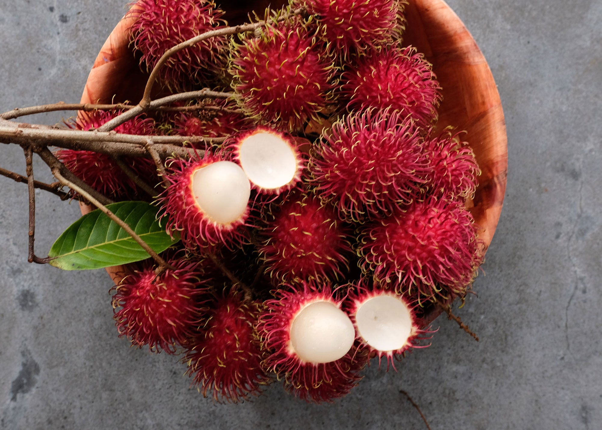Fresh rambutan fruit from Hawaii. Image of fresh rambutan in a bowl with a few fruits peeled open to show the flesh of the fruit.